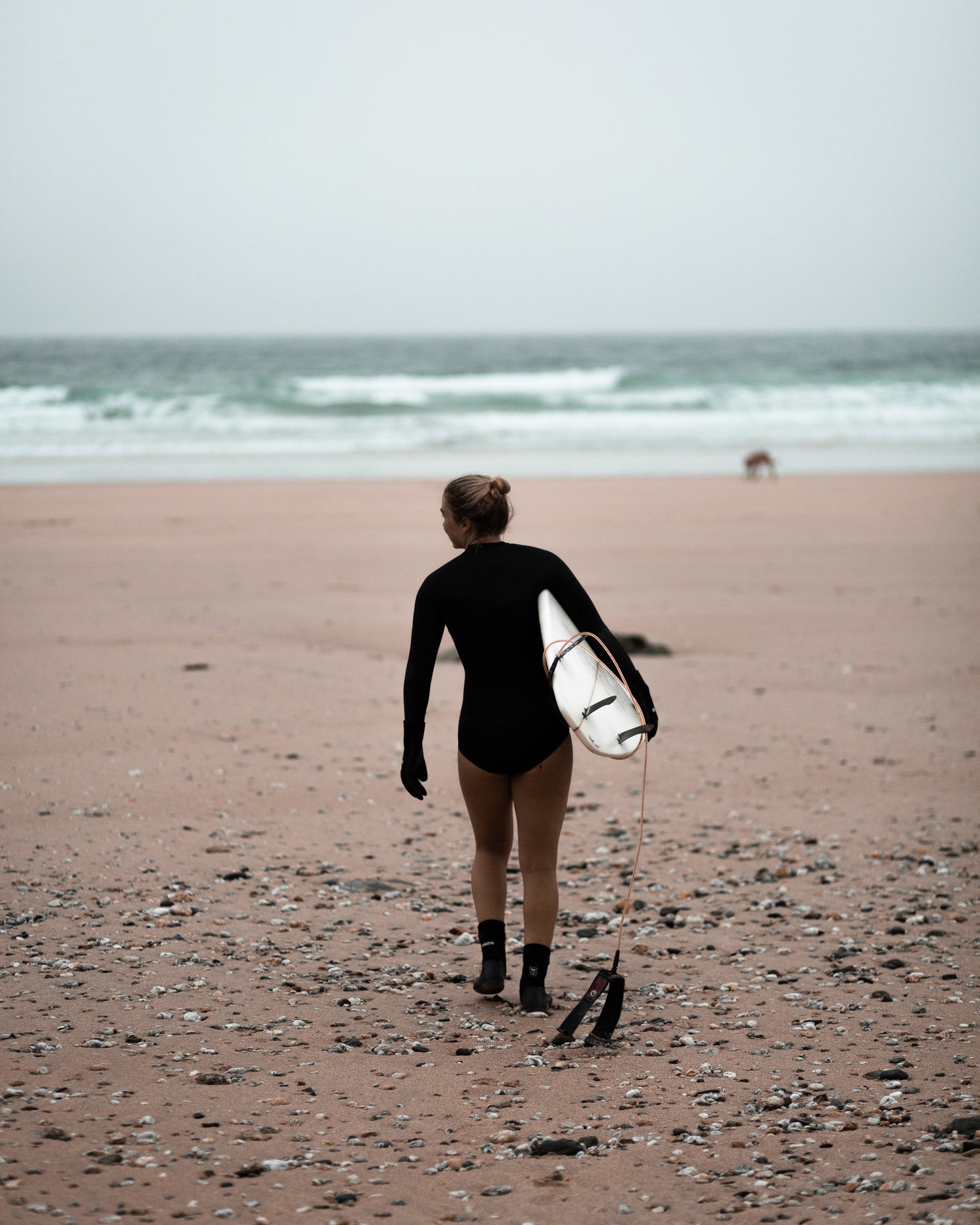 Surfer walking on the beach after getting some waves surfboard mounts from www.noir.design