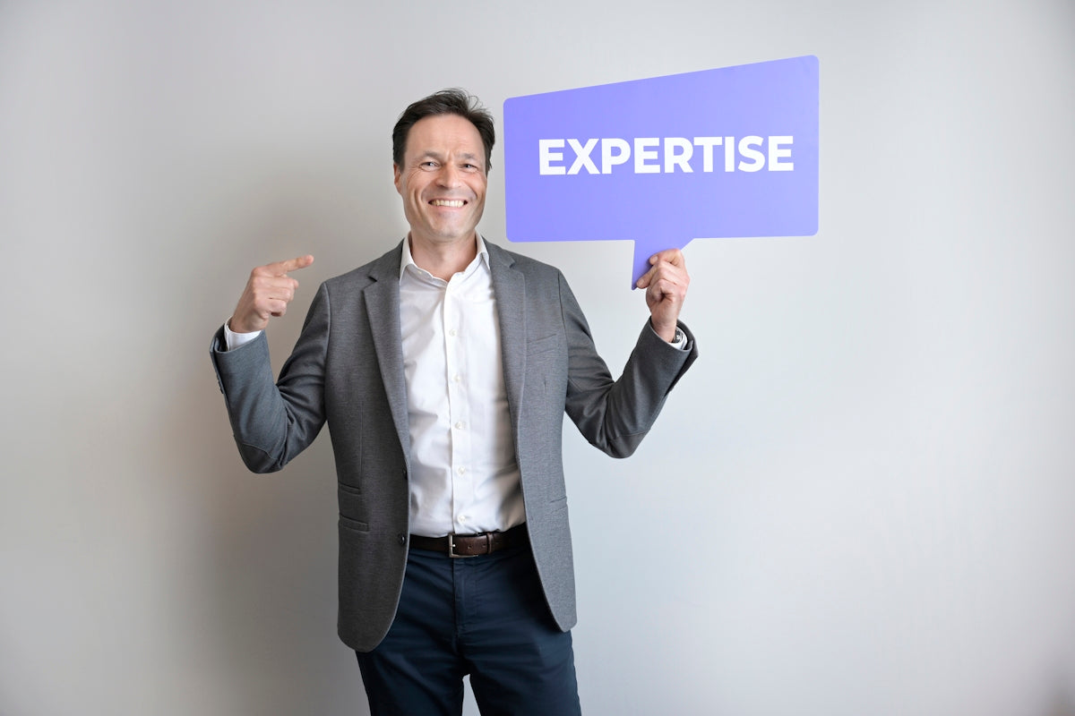 A man points to himself holding an expertise sign.