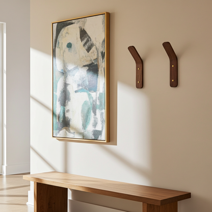 Abstract painting on a wall with wooden hooks and a bench below.