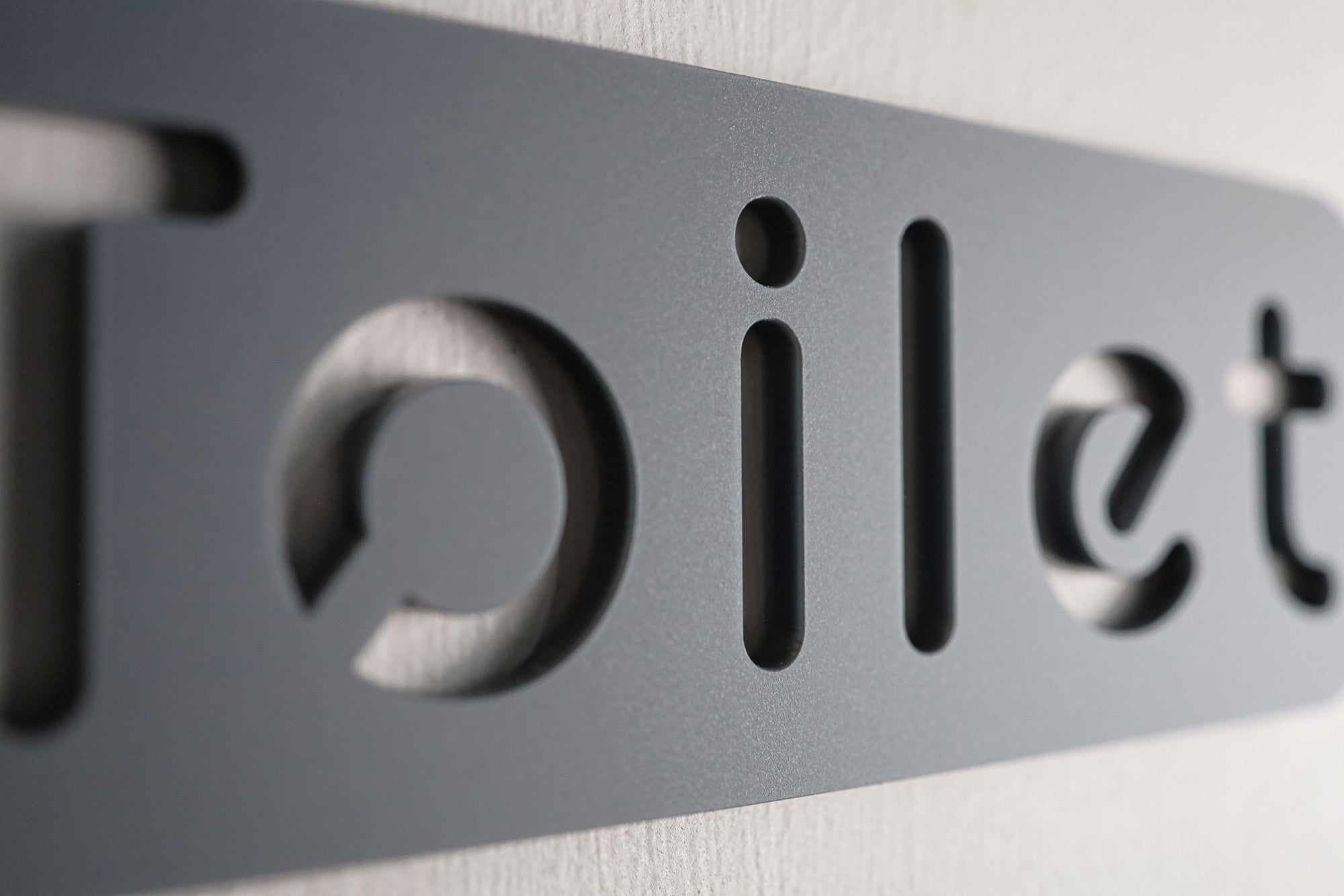 Stylish bathroom sign with a contemporary stone texture and simple, clean lettering.