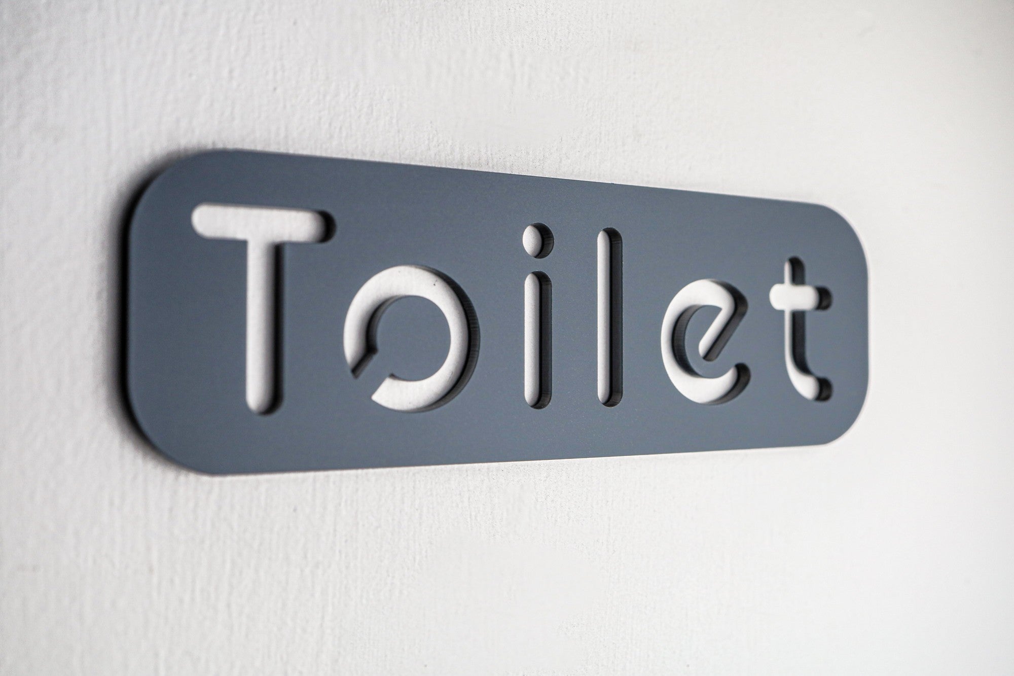Premium grey acrylic toilet sign with self-adhesive backing for easy installation.