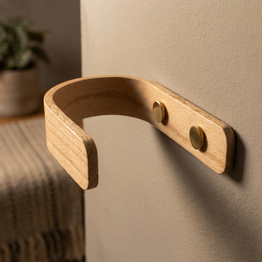 Wooden wall hook with brass screws on a beige wall