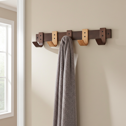 Wall-mounted coat rack with hooks holding a gray scarf against a neutral wall.